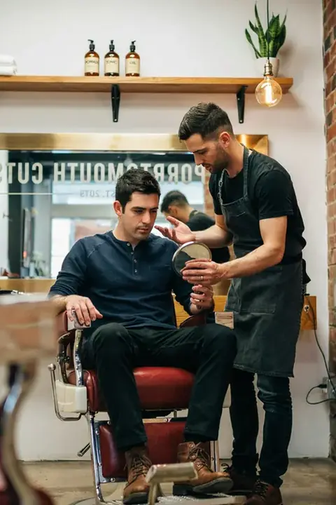 Cliente hablando con su barbero en la barbería durante una consulta