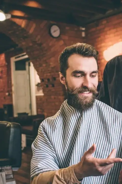 Cliente mostrando una foto de referencia al barbero en su teléfono
