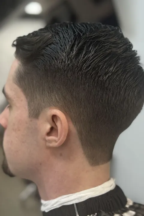 Hombre con corte taper fade visto de lado en la barbería