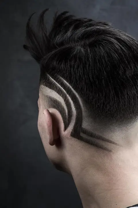 Taper fade con diseño freestyle de líneas curvas en la nuca