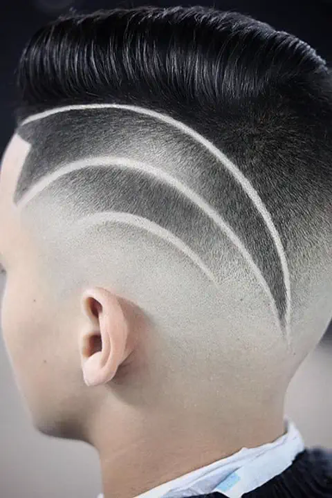 Taper fade con tres líneas paralelas curvas diseñadas en el degradado