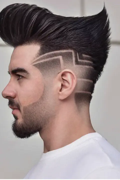 Taper fade con líneas geométricas angulares estilo greca en la sien