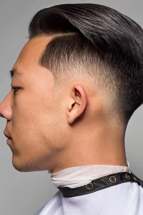 Taper fade con raya lateral y cabello peinado hacia atrás Taper fade con raya lateral y cabello peinado hacia atrás
